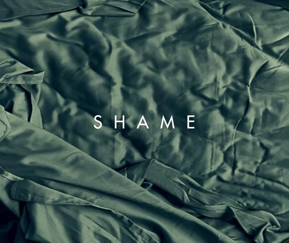 The word "shame" stands out on a vibrant green blanket